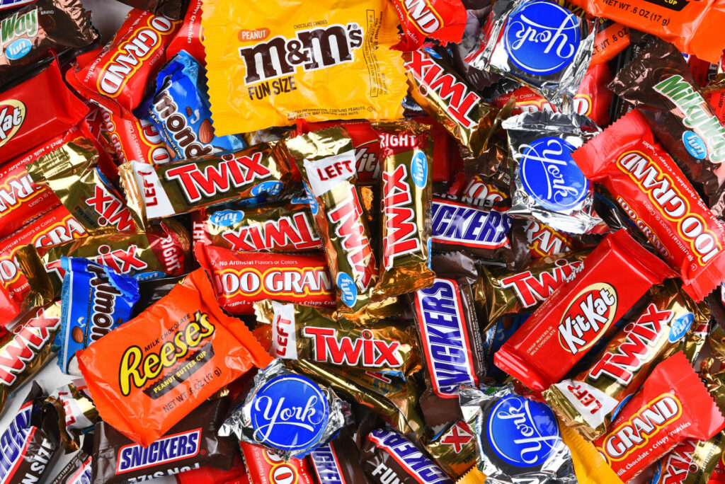 Assorted Halloween candy including M&Ms, Twix, Snickers, Kit Kat, Reese's, and other chocolate bars in colorful wrappers