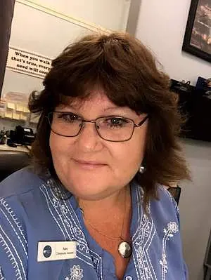 Amy smiling, in glasses and a blue patterned top with her name badge